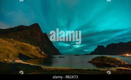 Aurora sulla spiaggia sabbiosa haukland, Kvalvika e Skagsanden con pietre in Norvegia, Isole Lofoten. Luci del nord in isole Lofoten in Norvegia. Cielo stellato con luci polari. Paesaggio notturno con green aurora borealis, rocce, illuminazione. Foto Stock