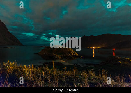 Aurora sulla spiaggia sabbiosa haukland, Kvalvika e Skagsanden con pietre in Norvegia, Isole Lofoten. Luci del nord in isole Lofoten in Norvegia. Cielo stellato con luci polari. Paesaggio notturno con green aurora borealis, rocce, illuminazione. Foto Stock