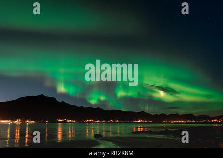 Aurora sulla spiaggia sabbiosa haukland, Kvalvika e Skagsanden con pietre in Norvegia, Isole Lofoten. Luci del nord in isole Lofoten in Norvegia. Cielo stellato con luci polari. Paesaggio notturno con green aurora borealis, rocce, illuminazione. Foto Stock