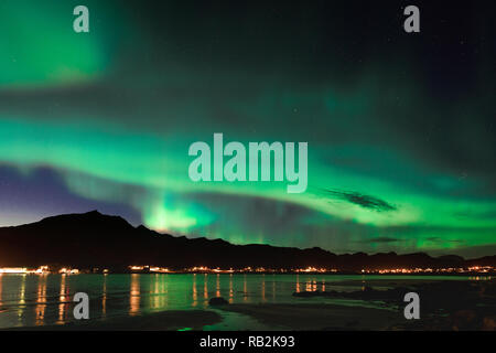 Aurora sulla spiaggia sabbiosa haukland, Kvalvika e Skagsanden con pietre in Norvegia, Isole Lofoten. Luci del nord in isole Lofoten in Norvegia. Cielo stellato con luci polari. Paesaggio notturno con green aurora borealis, rocce, illuminazione. Foto Stock