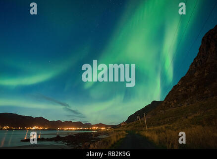 Aurora sulla spiaggia sabbiosa haukland, Kvalvika e Skagsanden con pietre in Norvegia, Isole Lofoten. Luci del nord in isole Lofoten in Norvegia. Cielo stellato con luci polari. Paesaggio notturno con green aurora borealis, rocce, illuminazione. Foto Stock