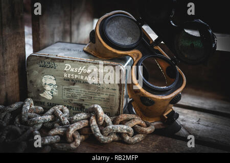 Vecchio gasmask, vintage googles e catene arrugginito in una scatola di legno. Rusty e il vecchio concetto vintage. Foto Stock