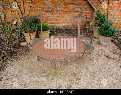 Tavolo in metallo e sedie nel giardino murato dietro i cottage vicino alle rovine di Cowdray House, Midhurst, West Sussex, Regno Unito Foto Stock