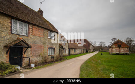 Cottage e un tradizionale grain store oltre le rovine di Cowdray House, Midhurst, West Sussex, Regno Unito Foto Stock