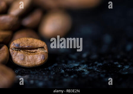 Chicchi di caffè nero su sfondo marmo, fotografia macro, spazio per un logo immagine o testo Foto Stock