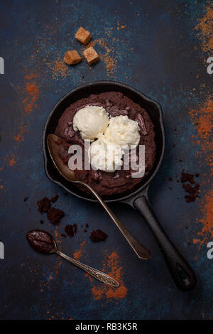 Brownie con crema di cioccolato e gelato alla vaniglia in una pentola su sfondo blu. vista dall'alto. Foto Stock