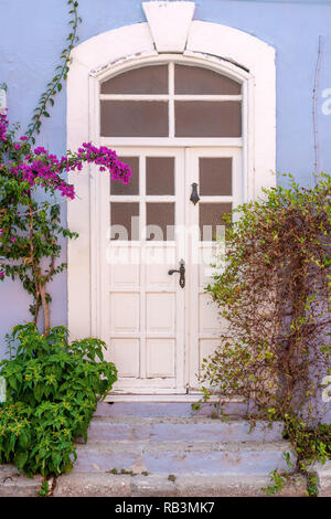 Porta decorata con vasi di fiori su una parete blu Foto Stock