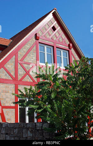 Gable lato di una casa in legno e muratura in costruzione, con dipinto di rosso gli elementi in legno Foto Stock