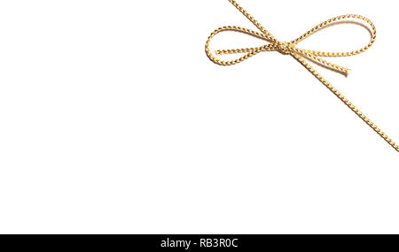Golden corda satinata angolo superiore destro con annodato dono di prua di avvolgimento a nastro per il regalo di Natale con intricati dettagli shine isolato tagliato fuori vista superiore su Foto Stock