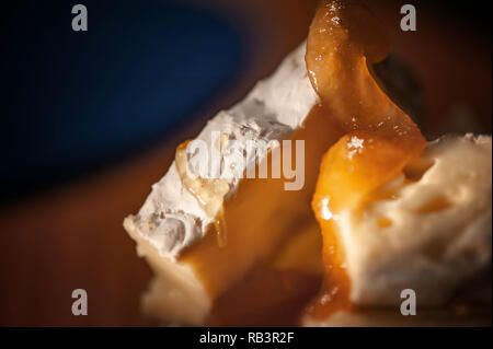 Camembert cremoso con miele su un rustico sfondo di legno. Close-up shot dettagliati. Foto Stock