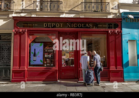 Due persone in cerca nella finestra del deposito Nicolas, a commercianti di vino shop on Rue Saint-Louis en l'Île,Paris , Francia Foto Stock