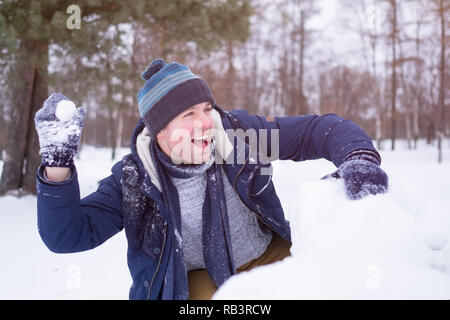 Unione uomo maturo in vestiti caldi a giocare con la neve all'aperto. Divertimento per le vacanze invernali. Foto Stock