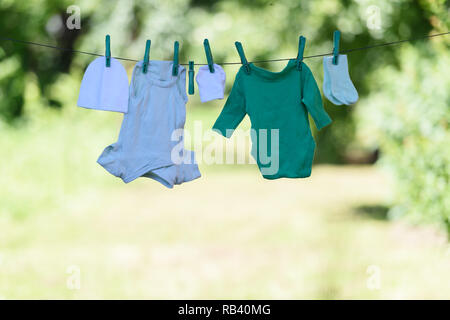 Vestiti del bambino su stendibiancheria essiccamento in giardino. Neonato concetto di infanzia Foto Stock