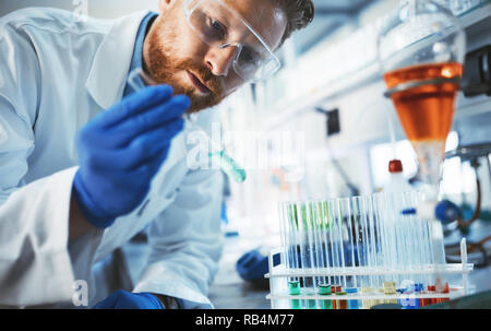 Studente di sesso maschile di lavorazione chimica in laboratorio Foto Stock