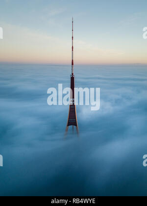 La riga di Radio e TV Tower in Riga, Lettonia è il più alto torre nell'Unione europea. Suggerimento spuntavano di nebbia strato durante la bellissima alba. Foto Stock