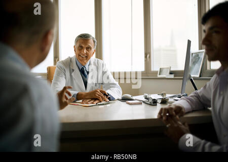 Senior consulenza medico con i pazienti nel suo ufficio. Foto Stock