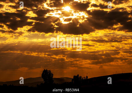 Il sole che splende attraverso basse nubi Foto Stock