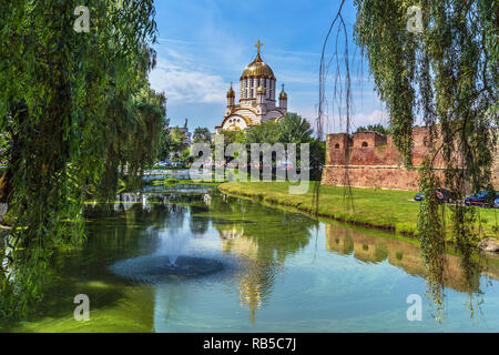 Bello scenario con una grande chiesa e un lago con alberi intorno in Romania Foto Stock