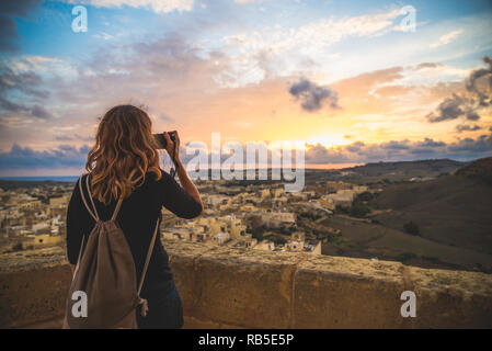 Ragazza turistica di scattare le foto di una splendida vista dalla cima di un castello medievale, Gozo Malta Foto Stock