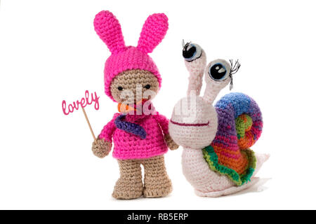 Ragazza a crochet Holding firmano incantevole e crochet rainbow lumaca, su sfondo bianco. Amigurumi. Fatte a mano Foto Stock