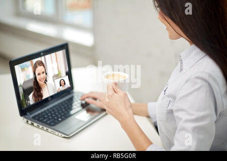 Donna di bere il caffè avente chiamata video su laptop Foto Stock