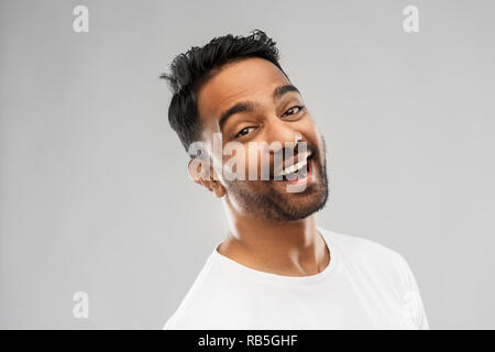 Giovani ridere uomo indiano su sfondo grigio Foto Stock