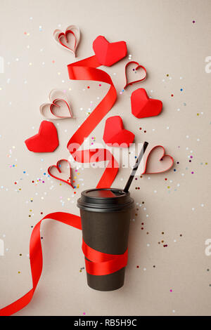 Carta Tazza da caffè decorato con Red origami Cuore, nastro di seta e coriandoli, amore prendere il via il caffè e il giorno di San Valentino, il concetto di spazio di copia Foto Stock