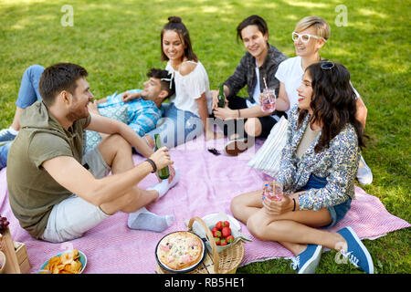 Happy amici con bevande al picnic nel parco di estate Foto Stock