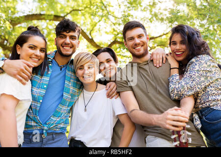 Happy amici con la chitarra in estate park Foto Stock