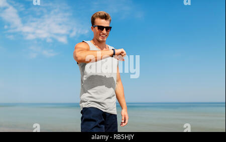 Uomo felice con tracker di fitness sulla spiaggia di estate Foto Stock