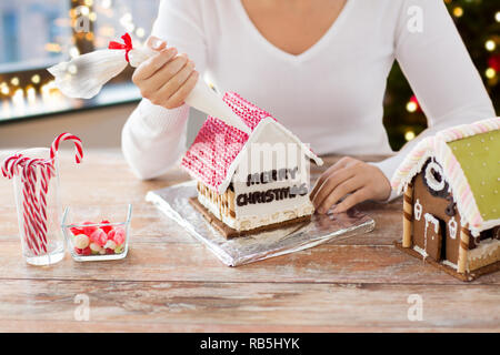 Donna che fa gingerbread house per natale Foto Stock