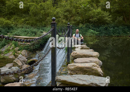 Uomo in meditazione alla bella cascata in natura su roccia brige in Wudangshan montagne. Cina Foto Stock