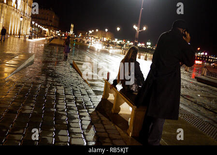 In attesa per il bus a Place de la Bourse - Stock Exchange Square, di notte, Bordeaux, Gironde, Francia Foto Stock