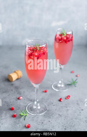 Melograno Champagne Cocktail Mimosa (Mocktail) con rosmarino su sfondo concreto, copia dello spazio. La Mimosa drink per il giorno di San Valentino o altri giorni festivi. Foto Stock