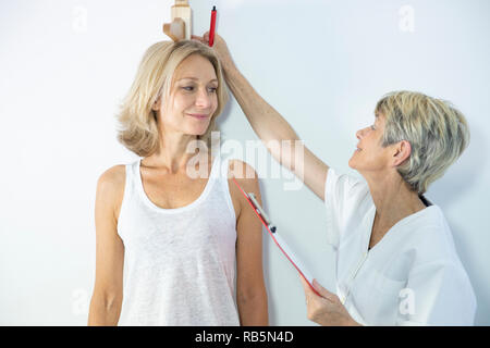 La donna stessa misura con una altezza dell'asta di misurazione. Foto Stock