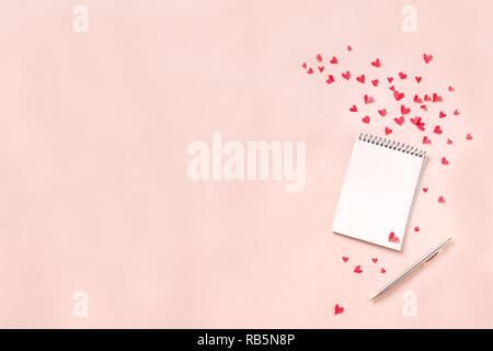 Notebook e cuori rossi isolato su sfondo beige, copia dello spazio. Minima laici piatta con la pianificazione per il giorno di San Valentino, amore e romanticismo concetto, vista dall'alto Foto Stock