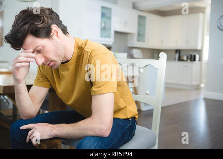 Preoccupato uomo seduto a casa Foto Stock