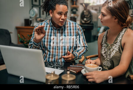 Gli imprenditori di parlare e di essere espressive in un caffè cafe con laptop parlando durante una riunione e di essere espressive in un caffè cafe con il computer portatile Foto Stock