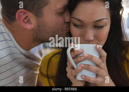 Uomo di baciare la donna in cucina Foto Stock