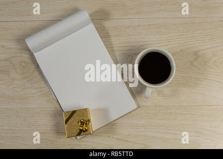 Confezione regalo, notepad e caffè nero sul tavolo di legno Foto Stock