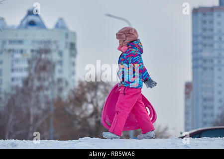 Bambina correre sulla neve slitte in inverno Foto Stock