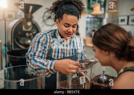 La tostatura del fagiolo conoscitore permettendo al cliente di annusare l'aroma del caffè in grani Foto Stock