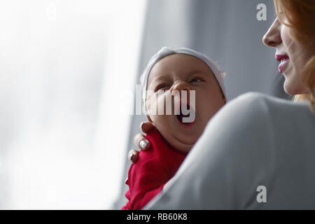 Amorevole Madre Cuddling Sleeping Neonato figlia sulla spalla. Foto Stock