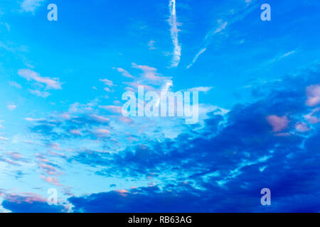 Modello di colore blu scuro, rosa e bianco delle nuvole, aereo sentieri sul cielo blu Foto Stock