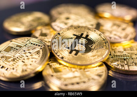 Pila di bitcoins giacente sulla lucida superficie scura Foto Stock