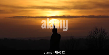 Il sole tramonta davanti al Sir Edward Carson statua a Stormont a Belfast. Foto Stock