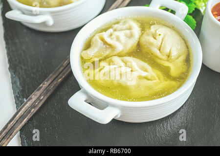 Asian canederli in brodo in una ciotola bianco. Messa a fuoco selettiva. Foto Stock