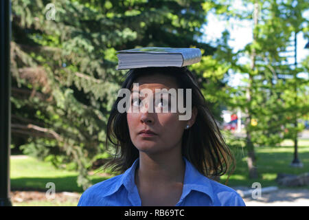 Brunette donna equilibratura di un libro sulla sua testa , Foto Stock