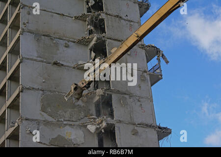 Costruzione gialla braccio gru demolendo un stripped down calcestruzzo appartamento edificio, Rabot, Gand, Belgio Foto Stock