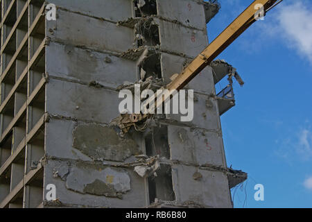 Costruzione gialla braccio gru demolendo un stripped down calcestruzzo appartamento edificio, Rabot, Gand, Belgio Foto Stock